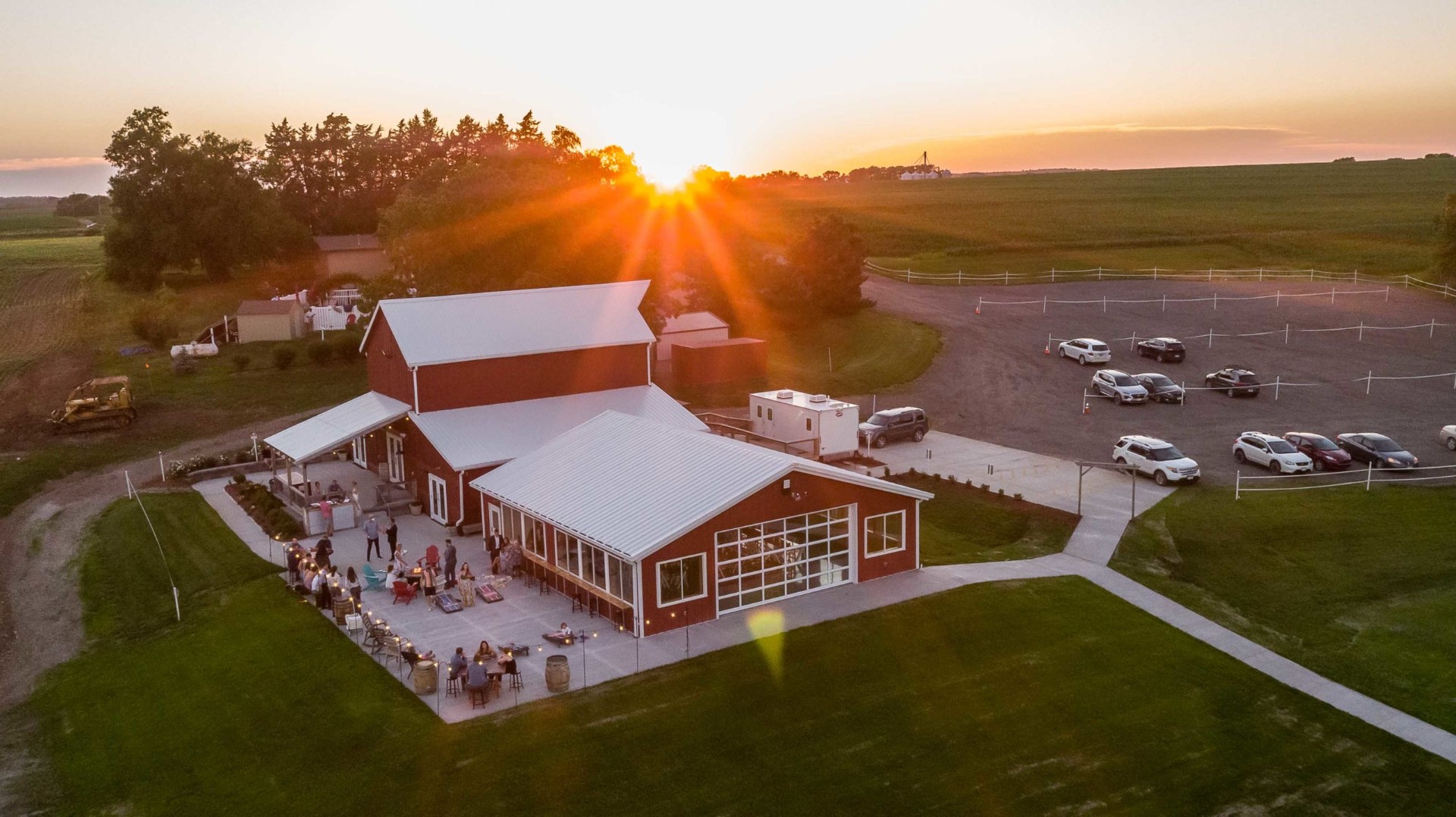 Sparks' Barn at sunset — aerial view of the red barn, patio, and Nebraska farmland.