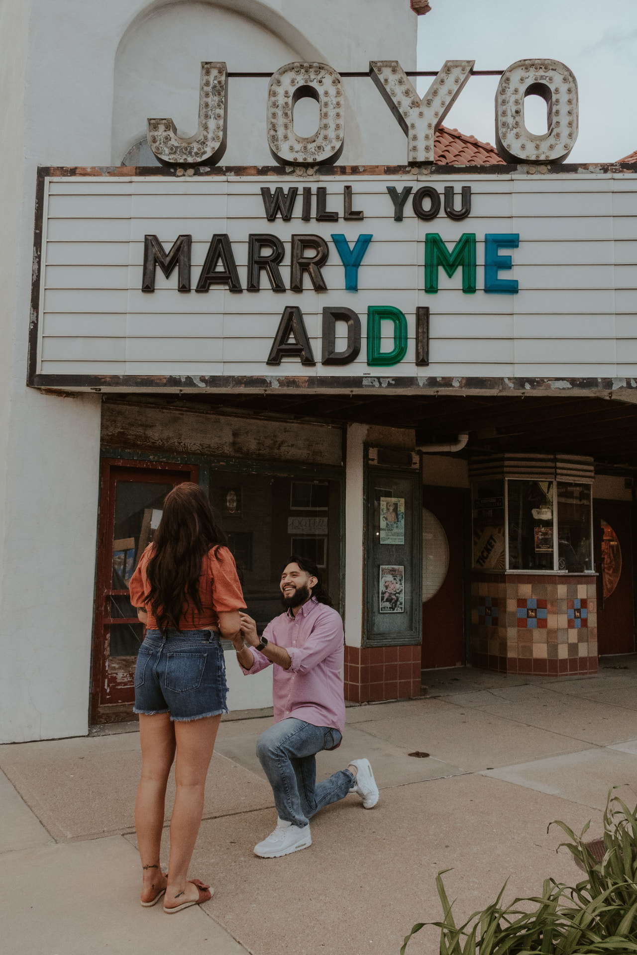 Geo on one knee proposing to Addi outside the Joyo Theater