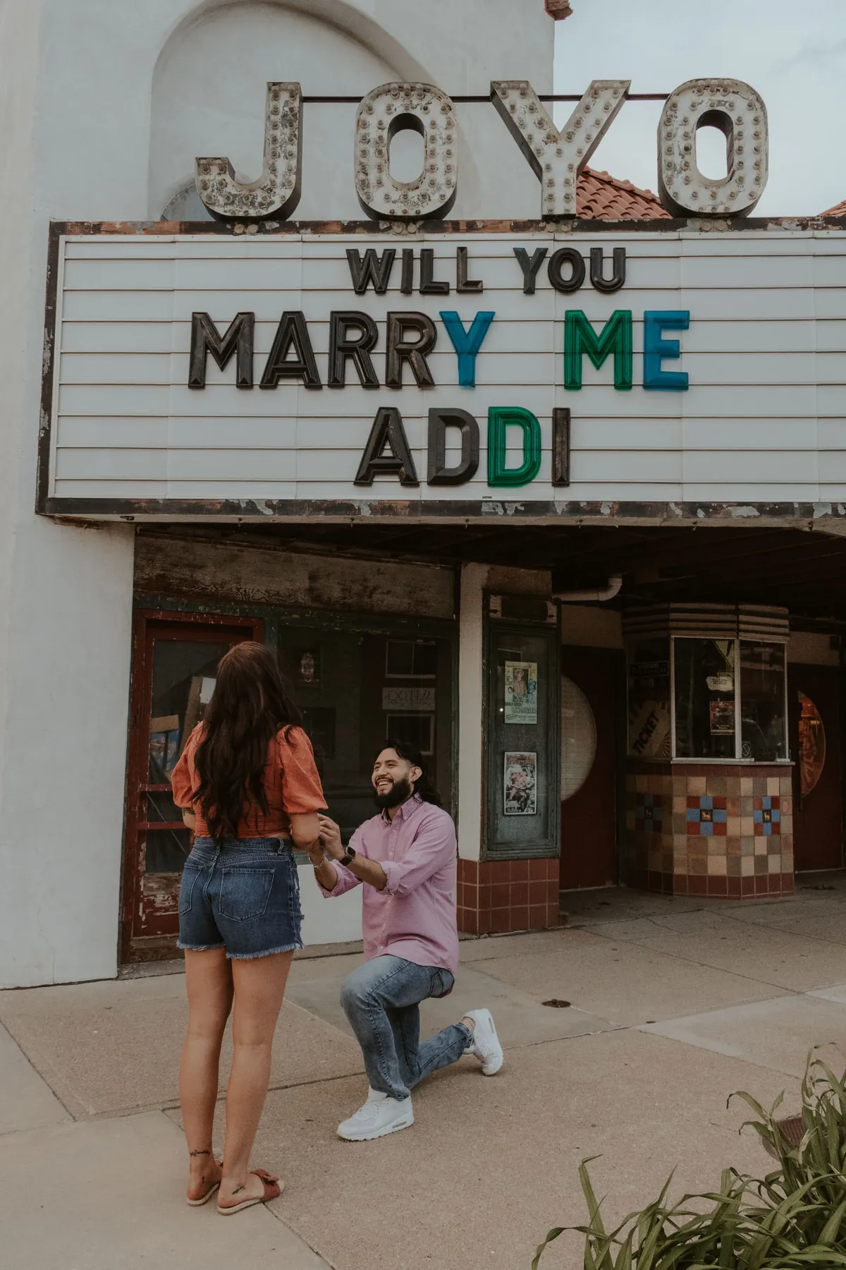 Geo on one knee proposing to Addi outside the Joyo Theater